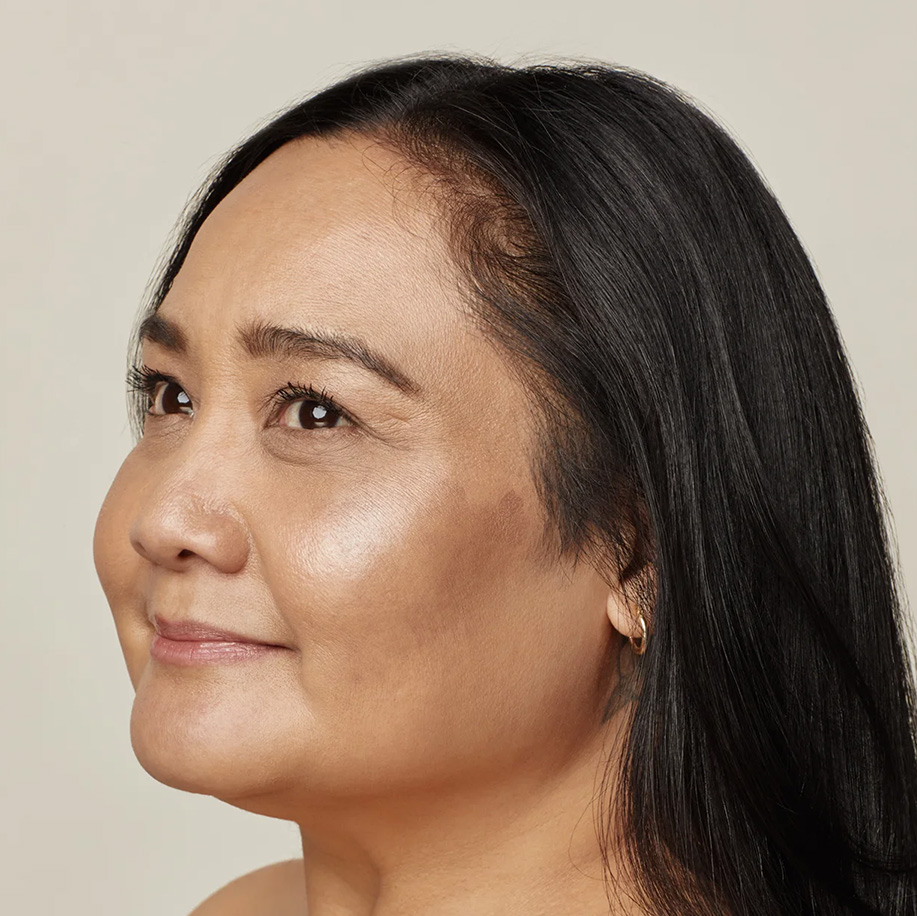 Side profile of an individual with healthy, luminous skin and dark hair, showing subtle cheekbone highlight. Represents natural skin clarity and glow.