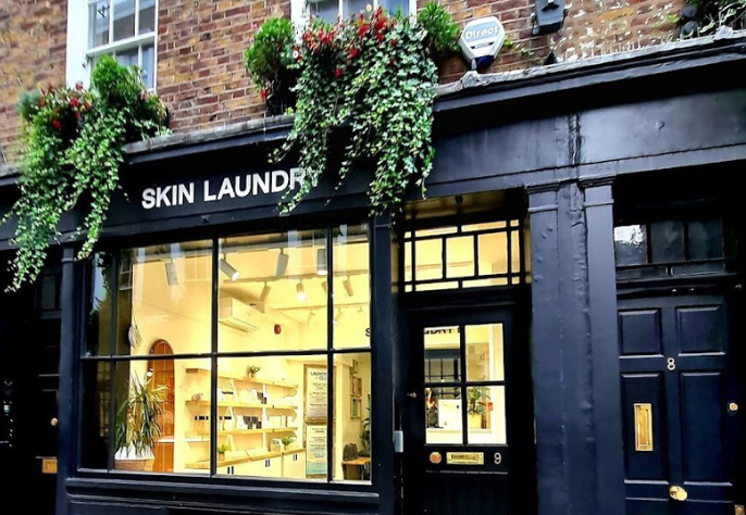 Exterior view of Skin Laundry skincare clinic with modern black storefront and large display window.