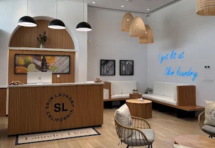 Chic Skin Laundry UAE clinic interior with modern wooden reception, seating area, and neon sign.
